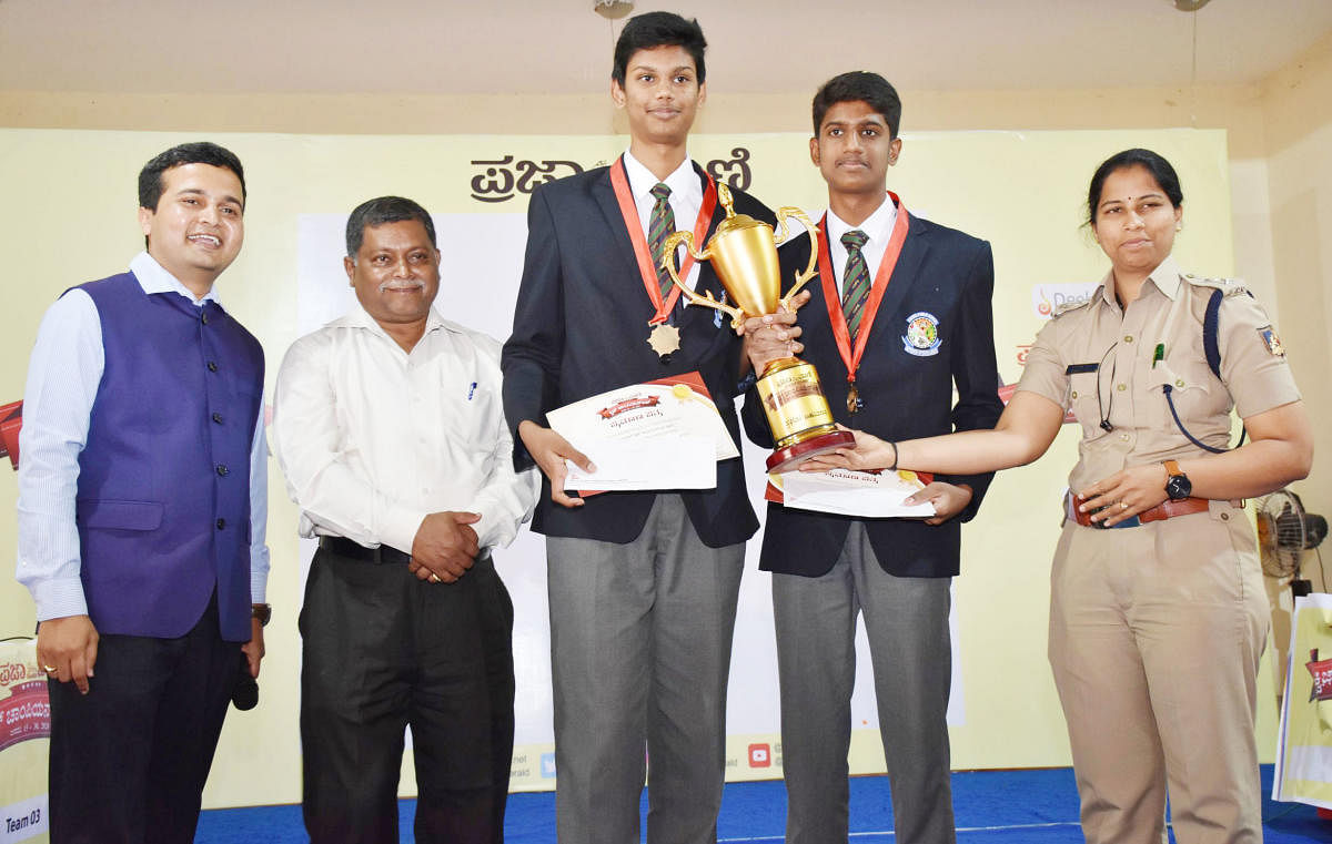 SP Suman D Pennekar distributes trophy to Amoghavarsha and Deepak Raj, who won the first place and entered the grand finale, in the Prajavani Quiz competition held at Maithri Community hall in Madikeri. DDPI P S Macchado, Quiz Master Sacchin Deshpande loo