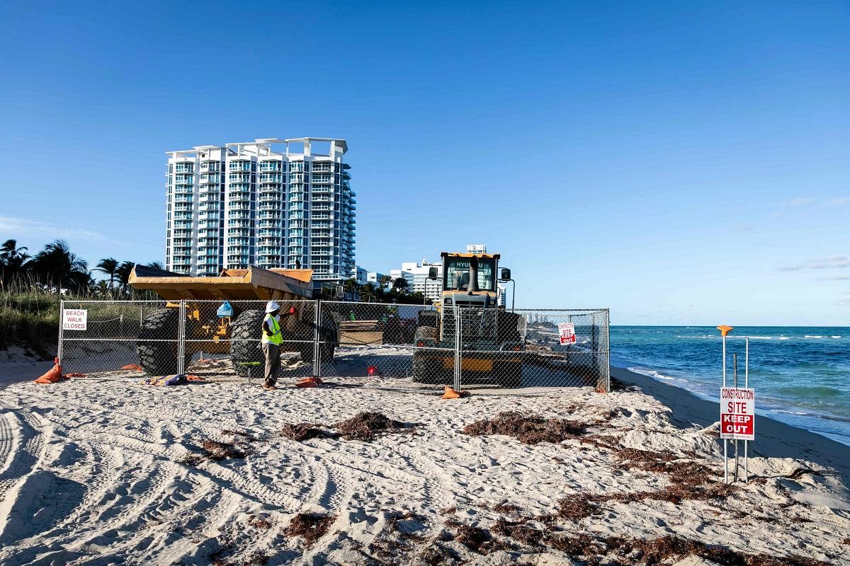 A worker stands near heavy machinery used dump sand on the shoreline of Miami Beach, Florida. (AFP PHOTO)