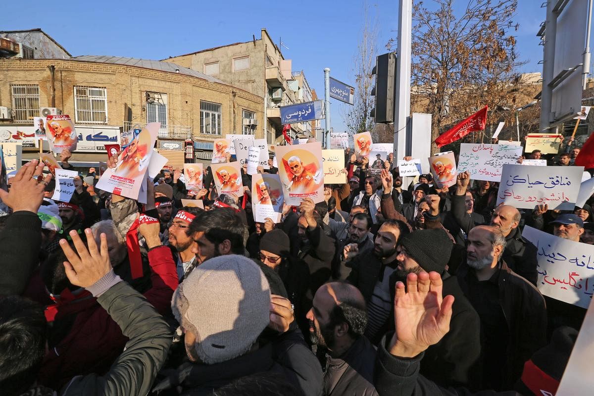 Iranian demonstrators hold placards bearing the image of slain military commander Qasem Soleimani in front of the British embassy in Iran's capital Tehran on January 12, 2020 following the British ambassador's arrest for allegedly attending an illegal dem