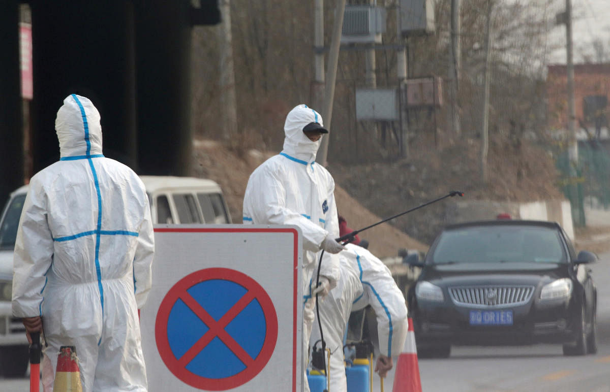 Workers in protective suits are seen at a checkpoint on a road leading to a village near a farm where African swine fever was detected, in Fangshan district of Beijing, China November 23, 2018. 9Ruters Photo)