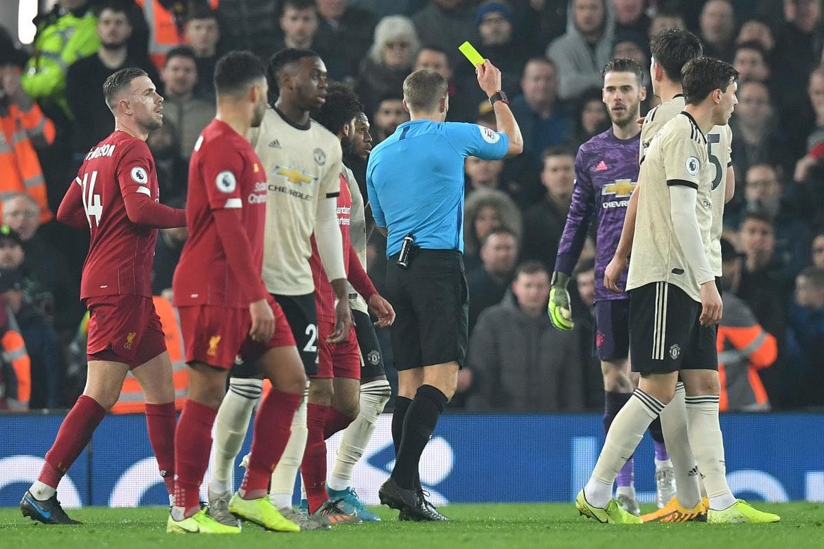 Referee Craig Pawson (C) books Manchester United's Spanish goalkeeper David de Gea (3R) for dissent during the English Premier League football match between Liverpool and Manchester United at Anfield stadium in Liverpool. AFP