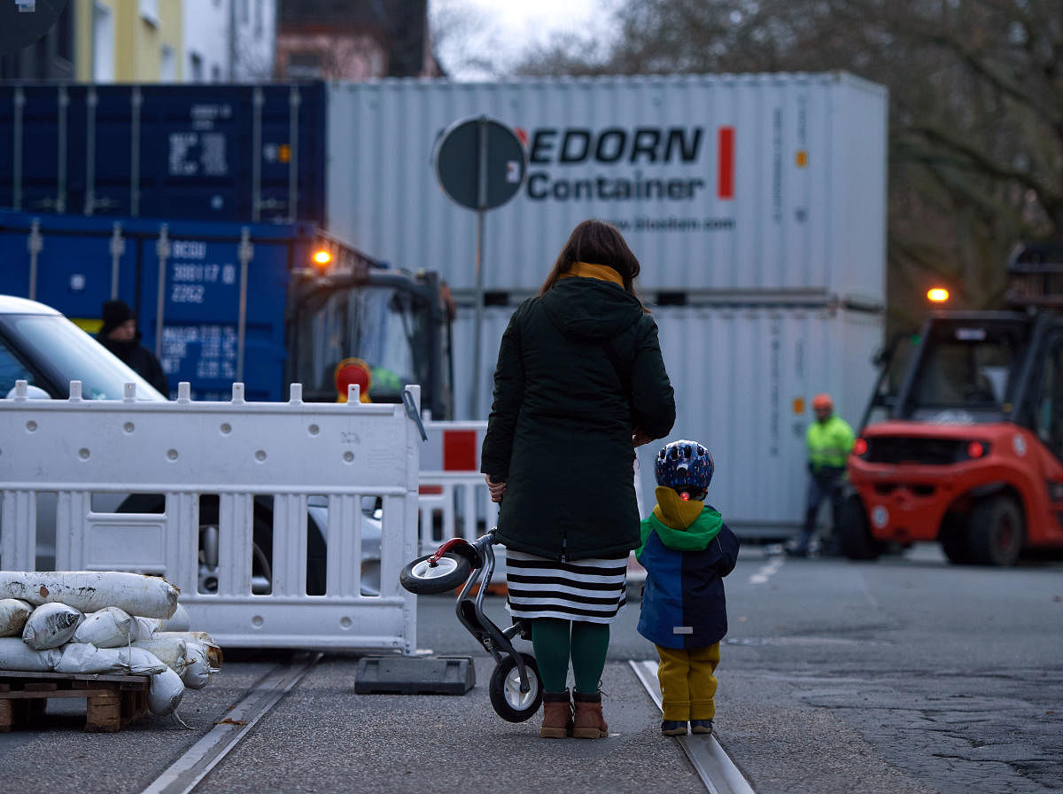 A woman and child stand in front of a wall made up of containers erected by workers to protect the houses in a street where World War II bombs were discovered in Dortmund, western Germany. (AFP Photo)