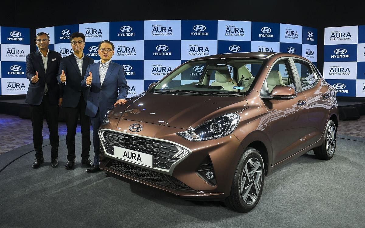 Hyundai Motors India MD &amp; CEO SS Kim (R), Executive Director Sales and Marketing DH Park (C) and Director -Sale and Marketing Tarun Garg (L) pose for photographs with the newly launched sedan Hyundai Aura, in New Delhi, Tuesday, Jan. 21, 2020. (PTI Ph