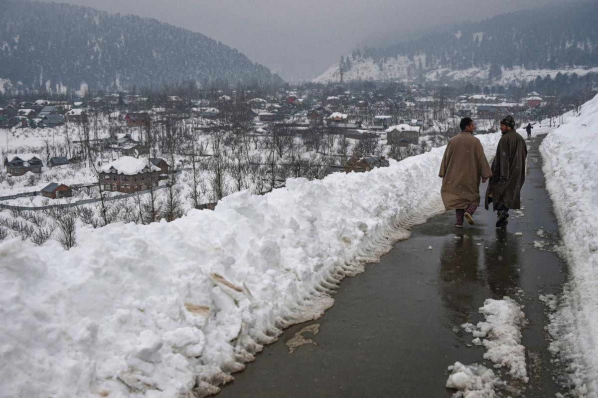 Men walk on a road along a snow covered village after heavy snowfall at Ferozpora, Tangmarg in Baramulla district of north Kashmir, Wednesday, Jan. 15, 2020. (PTI Photo)