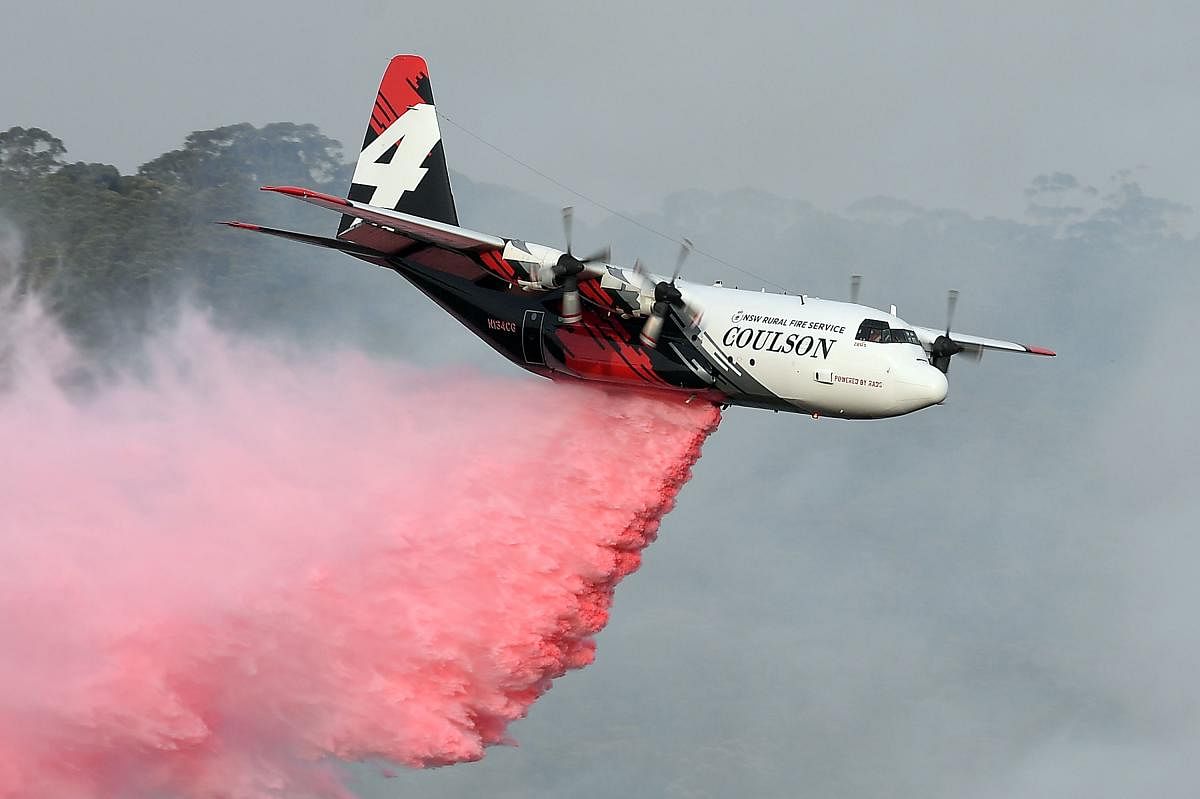 This file photo taken on January 10, 2020 shows a C-130 Hercules plane from the New South Wales Rural Fire Service dropping fire retardent to protect a property during an operation to douse bushfires in Penrose, in Australia's New South Wales state. (AFP