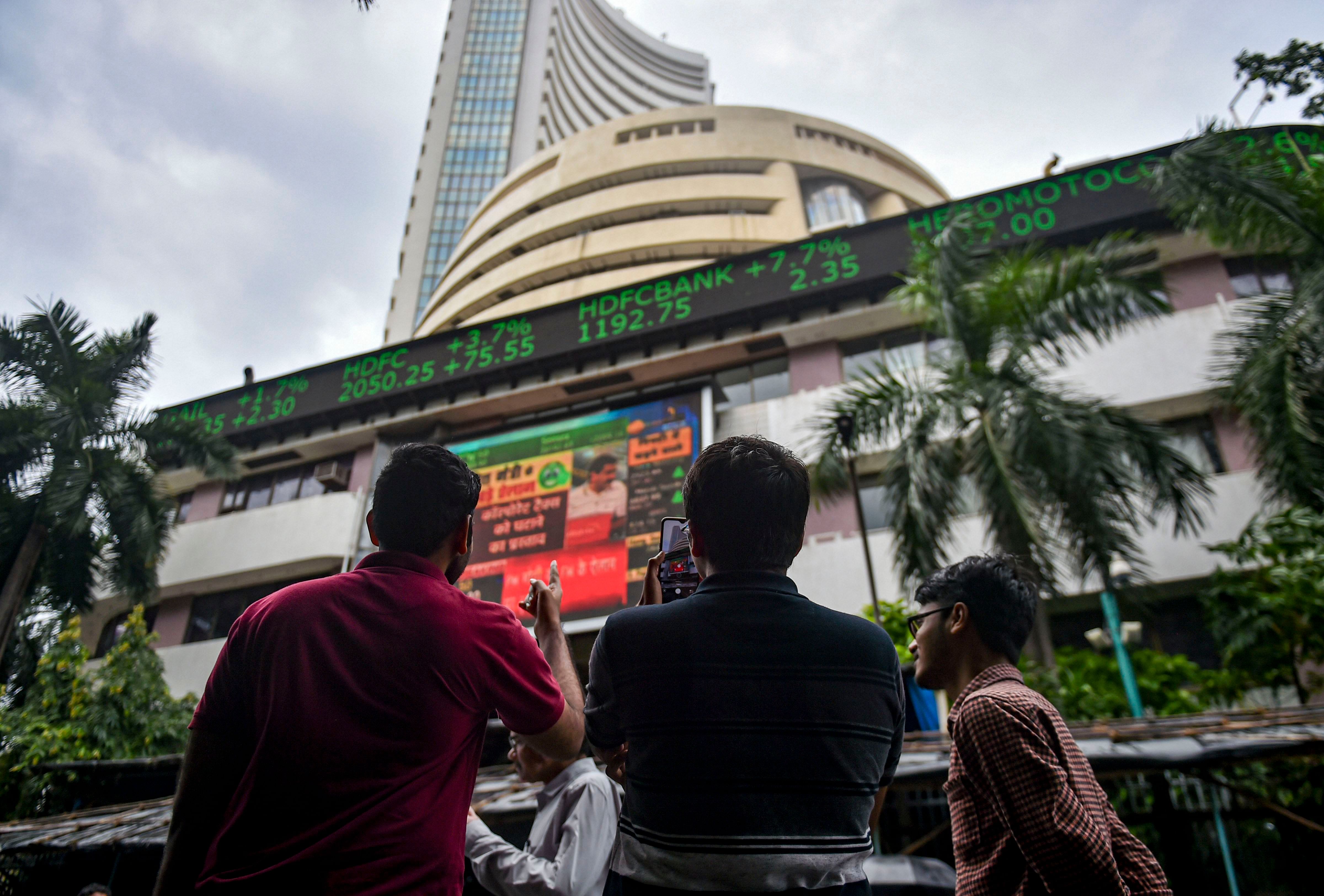 Bystanders react as they watch the stock prices displayed on a digital screen outside BSE building, in Mumbai. (PTI Photo)