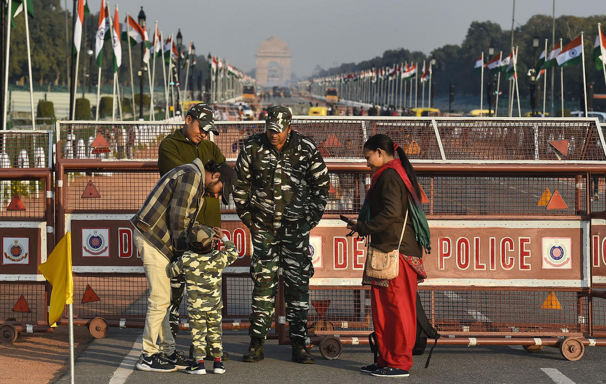 A child, donned in army uniform, interacts with security personnel standing guard at the Rajpath, which is all-set for the Republic Day Parade, in New Delhi. (PTI Photo)
