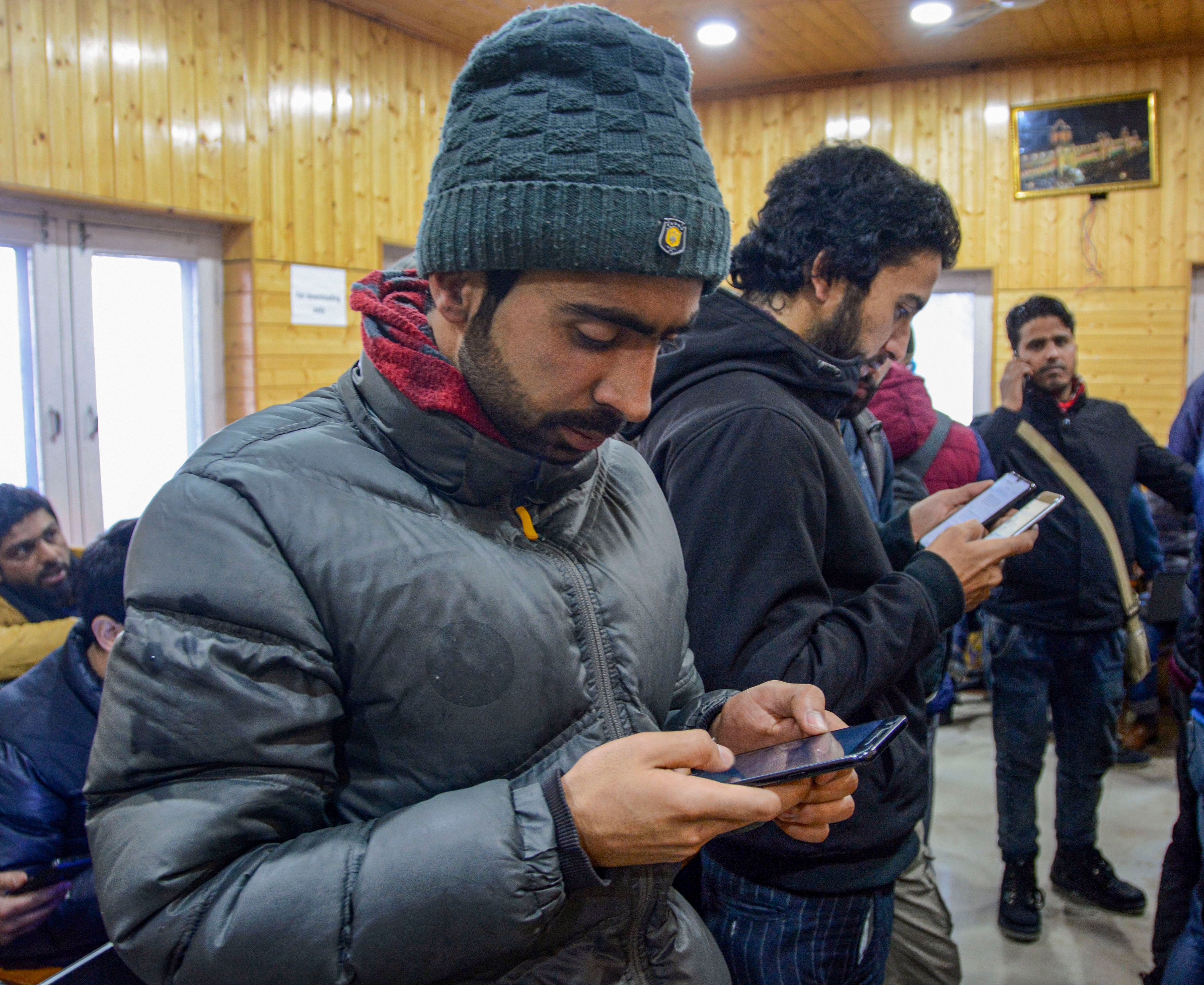 Journalists uses their mobile phone as government orders for the restoration of pre-paid mobile services and 2G internet services. (PTI Photo)