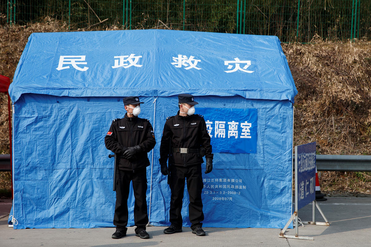 Security personnel stand in front of a disaster relief tent at a checkpoint in Yunxi county. Reuters