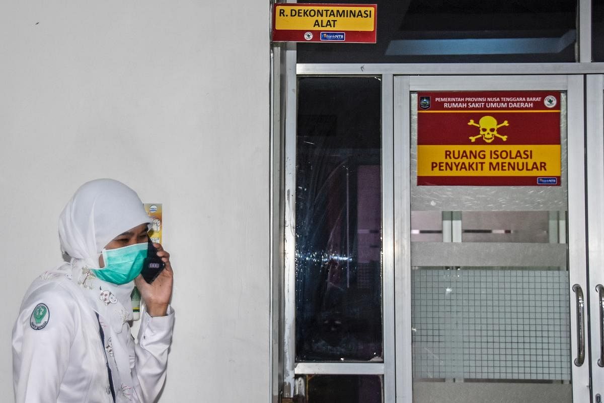 An Indonesian medical worker speaks on her phone outside an isolation area, to be occupied by patients showing symptoms of a deadly virus outbreak which began in the Chinese city of Wuhan, at a public hospital in Mataram, West Nusa Tenggara on January 28,