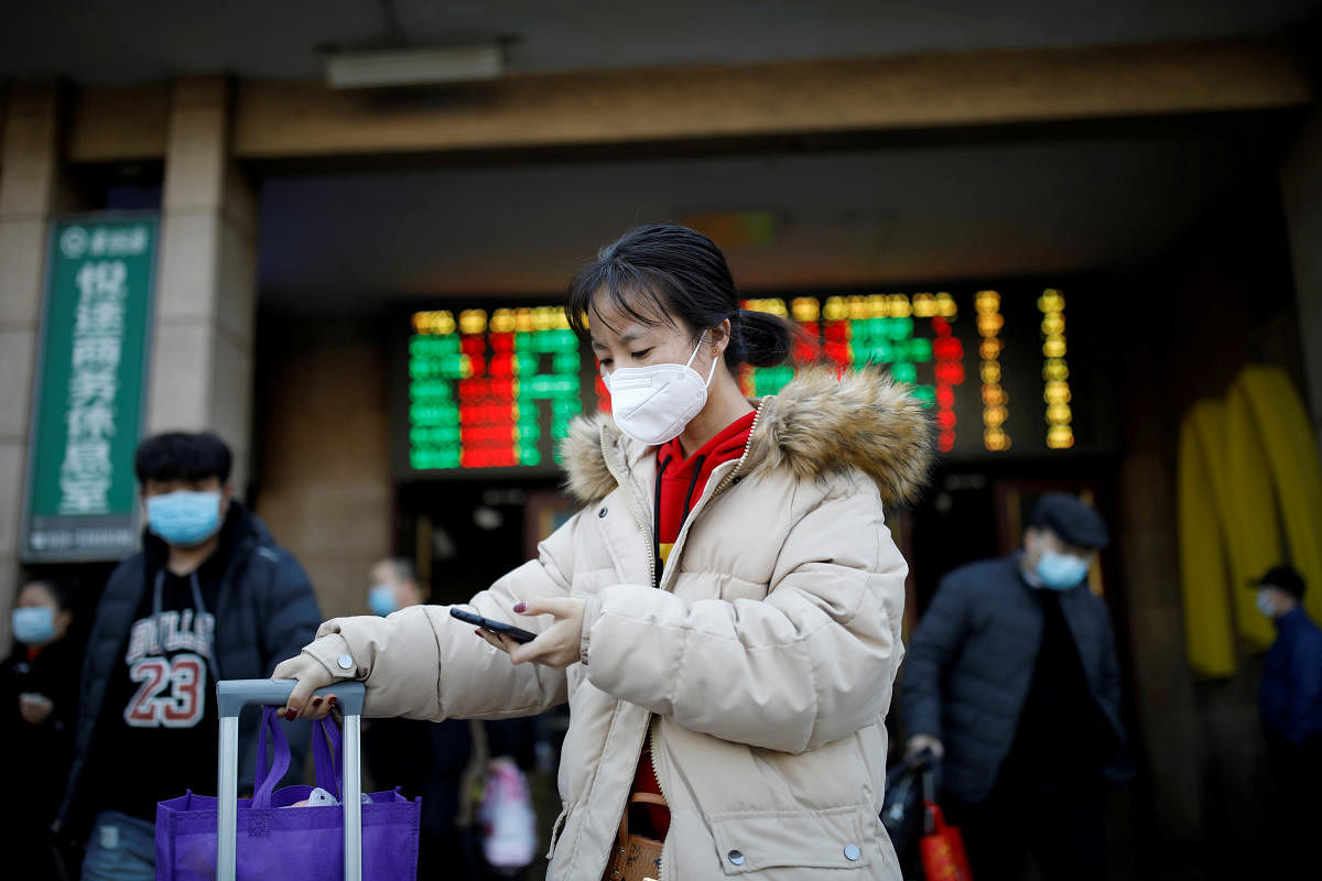 Woman wearing a face mask uses her cellphone as she walks outside Beijing Railway Station as the country is hit by an outbreak of the new coronavirus, in Beijing. Reuters