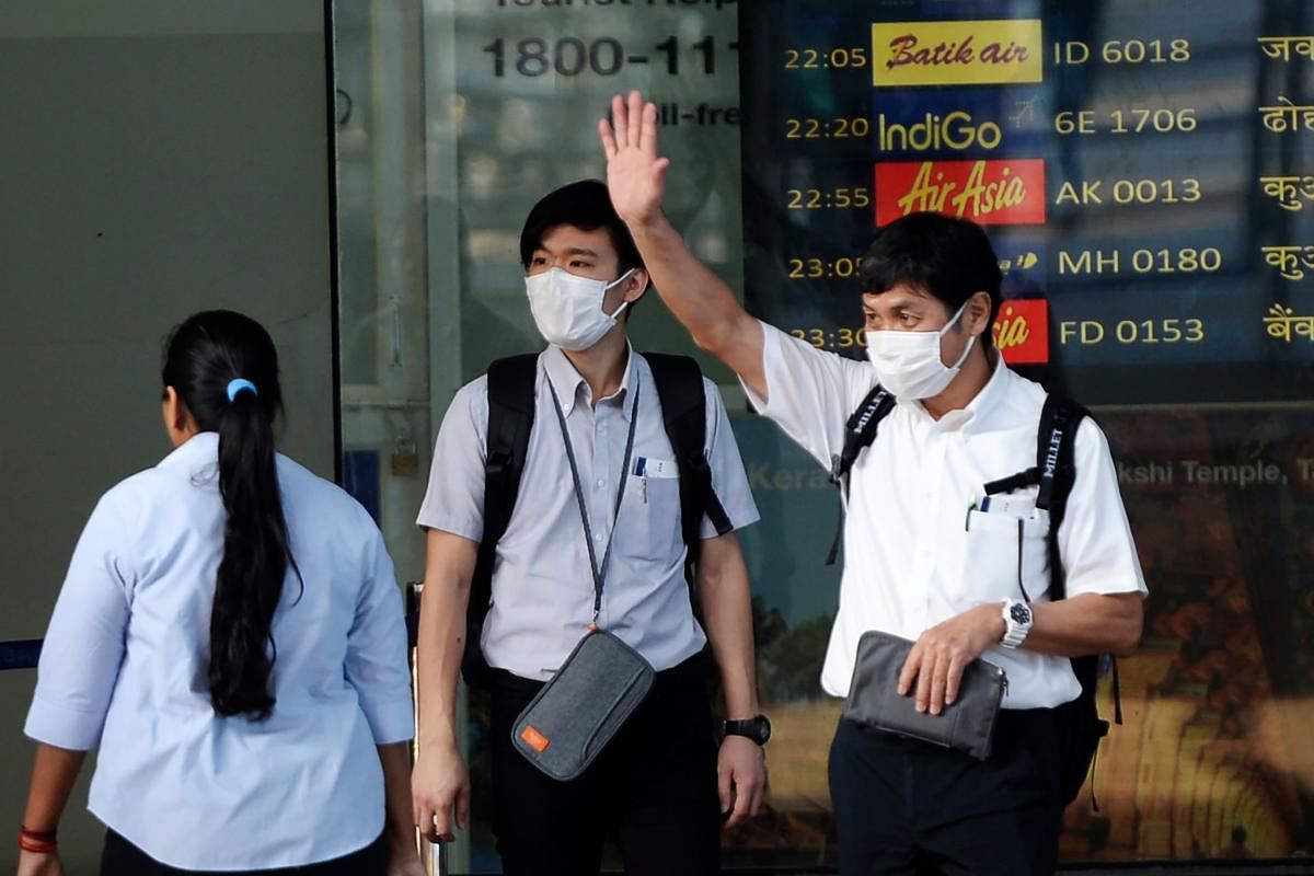 Travellers wearing face masks as prevention for the SARS-like virus outbreak which began in the Chinese city of Wuhan, stand outside Anna International airport in Chennai on January 31, 2020. (Photo by AFP)