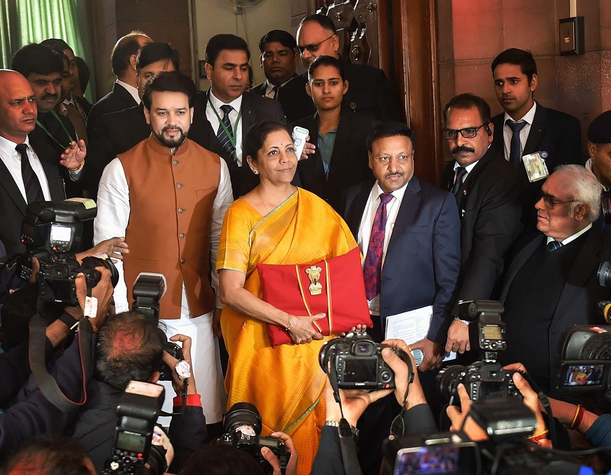 Union Finance Minister Nirmala Sitharaman, flanked by her deputy Anurag Thakur (to her right) and a team of officials, shows a folder containing the Union Budget documents, on her arrival at Parliament in New Delhi, Saturday, Feb. 1, 2020. (PTI Photo)