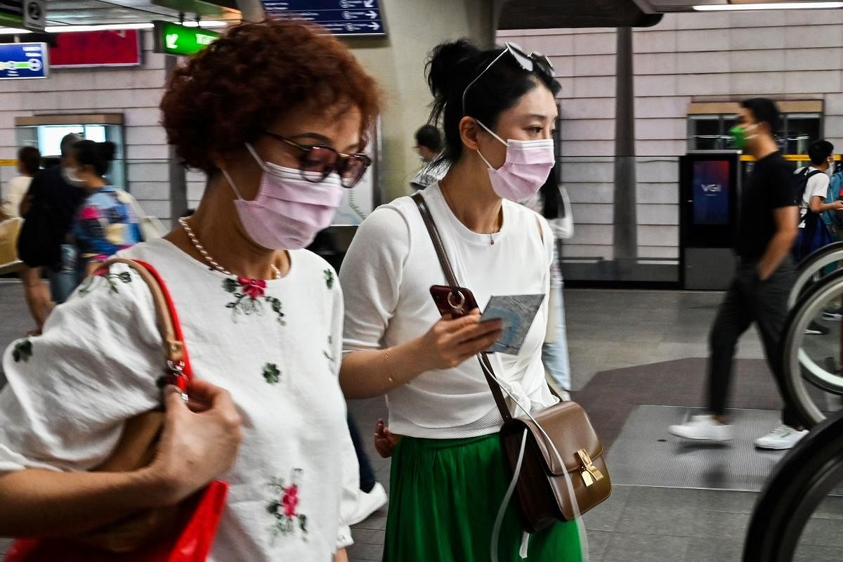 People wearing protective facemasks walk in a city commuter train station in Bangkok. AFP