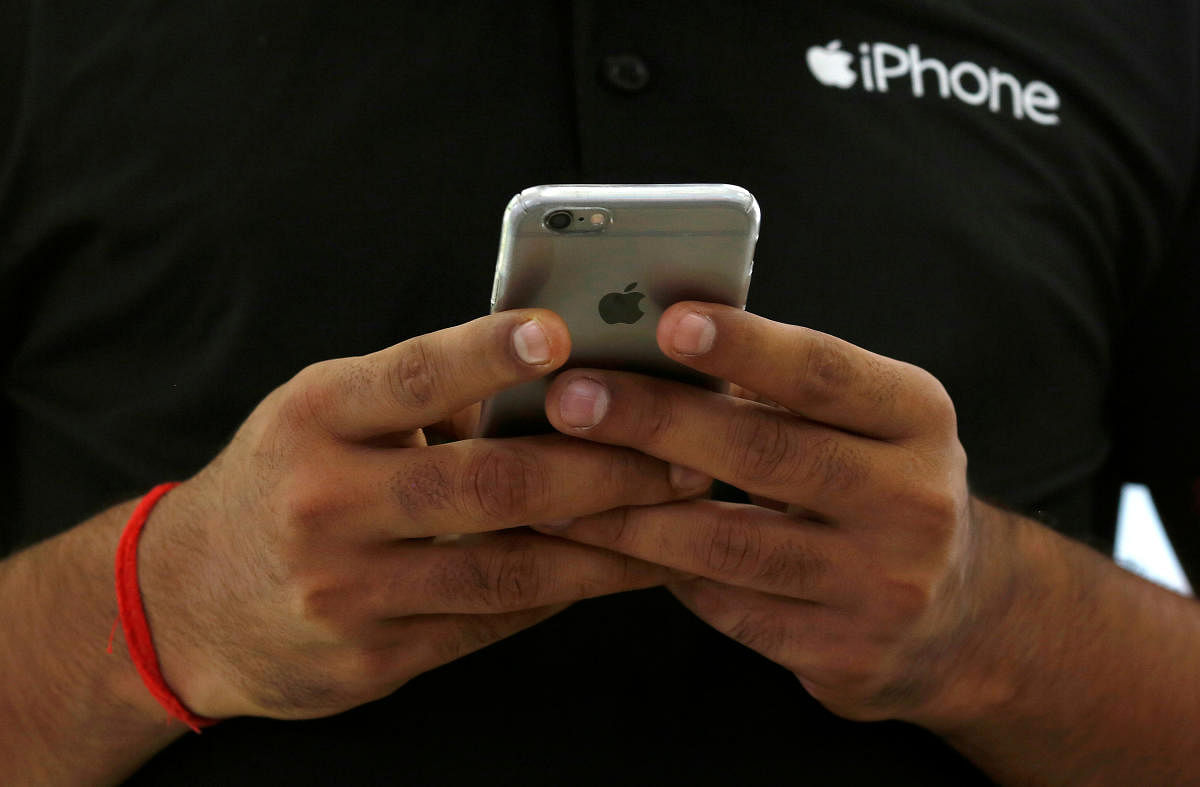 A salesman uses his iPhone at a mobile phone store in New Delhi (Credit: Reuters File Photo)