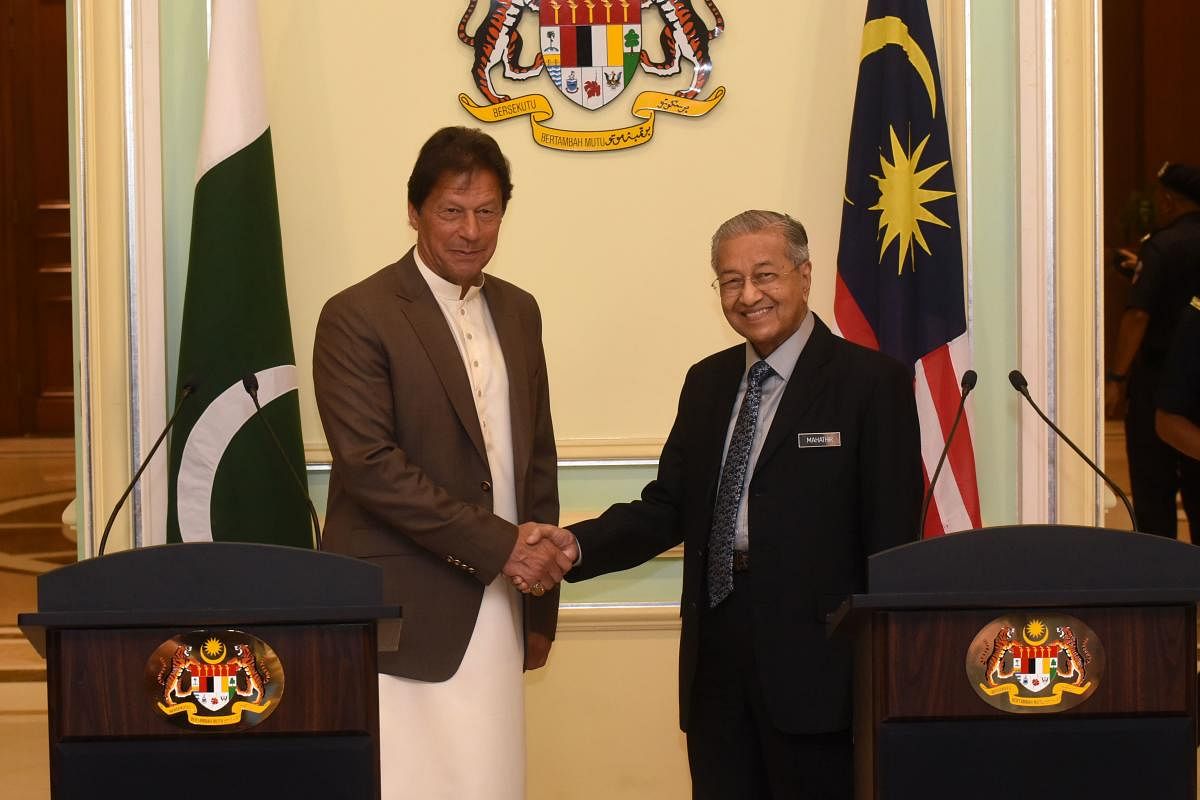 Malaysia's Prime Minister Mahathir Mohamad (R) shakes hands with Pakistan's Prime Minister Imran Khan after a joint press conference in Putrajaya. (Photo by Muhairul Azman Supian / Malaysia's Department of Information / AFP)