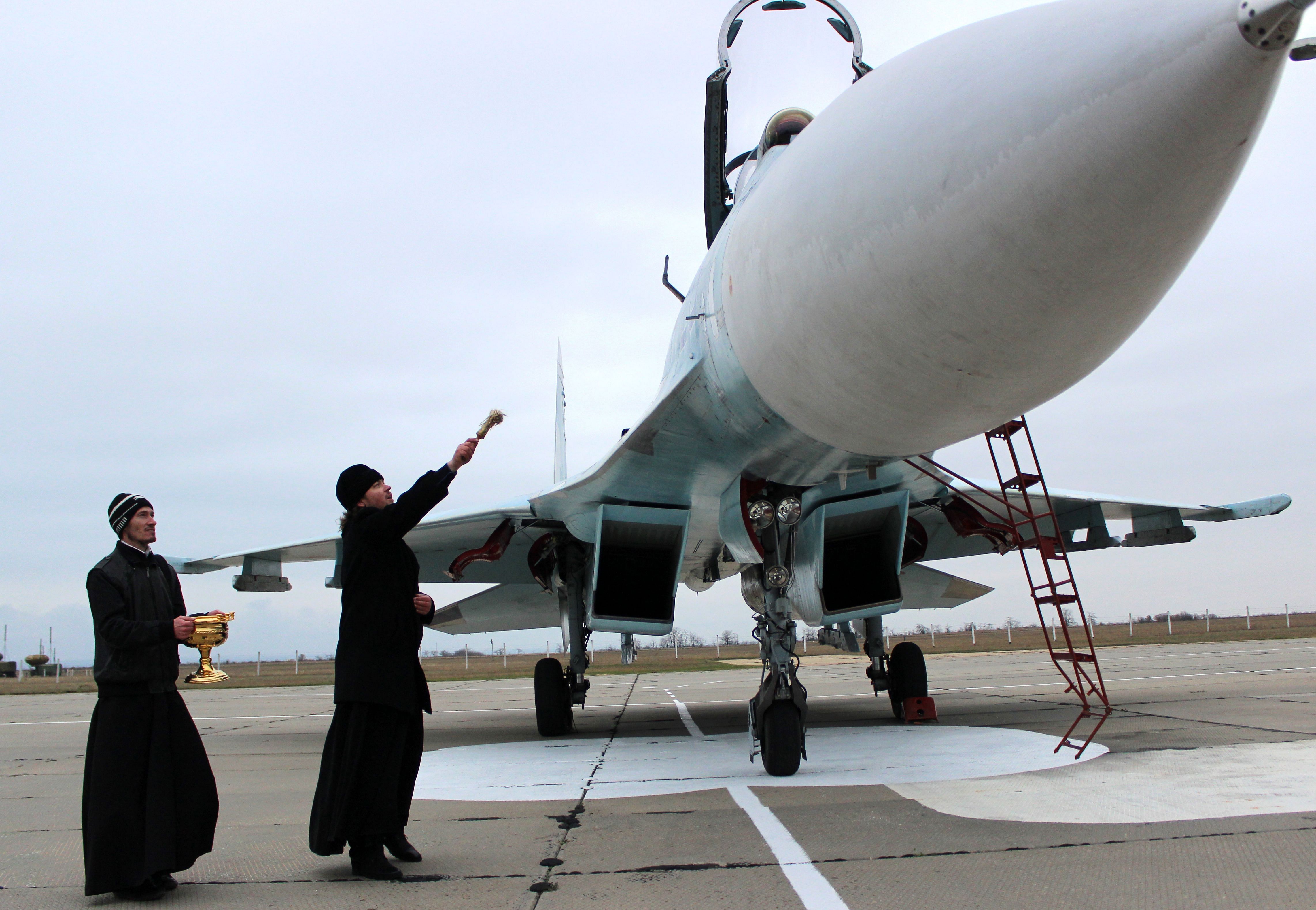 A Russian orthodox priest blesses a SU-27 SM fighter jet on the airfield of Belbek military airport outside Sevastopol, Crimea. (Credit: AFP Photo)