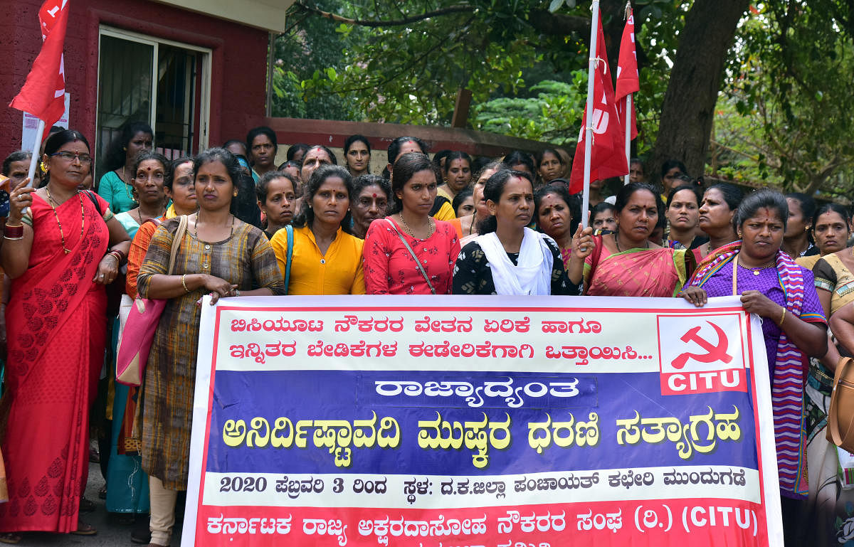 Members of Karnataka Rajya Akshara Dasoha Naukarara Sangha stage a protest in front of the Zilla Panchayat office in Mangaluru on Tuesday.