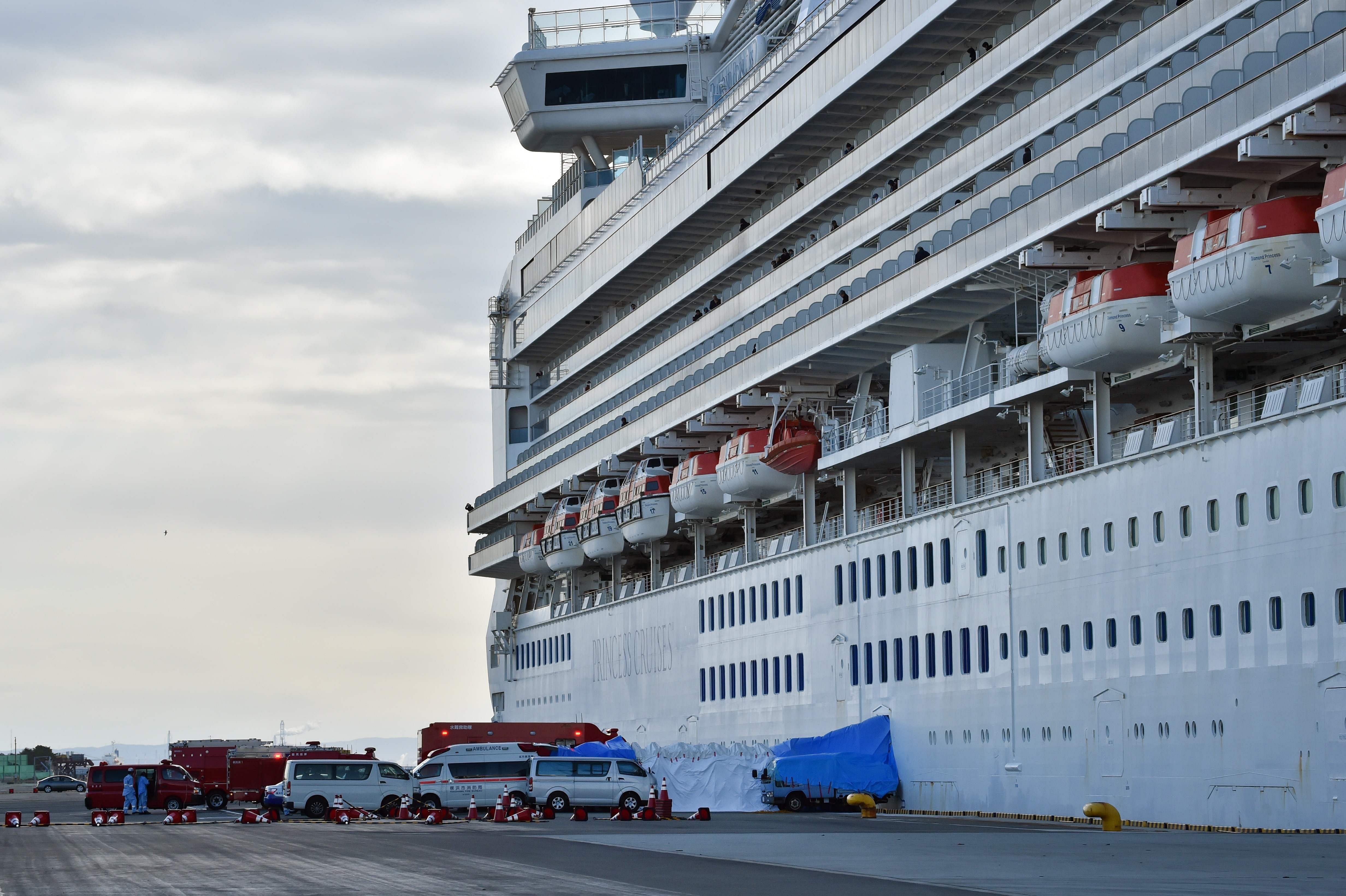 An ambulance (L) waits for patients who tested positive for the new coronavirus from the Diamond Princess cruise ship (R) at the Daikoku Pier Cruise Terminal in Yokohama. (AFP Photo)