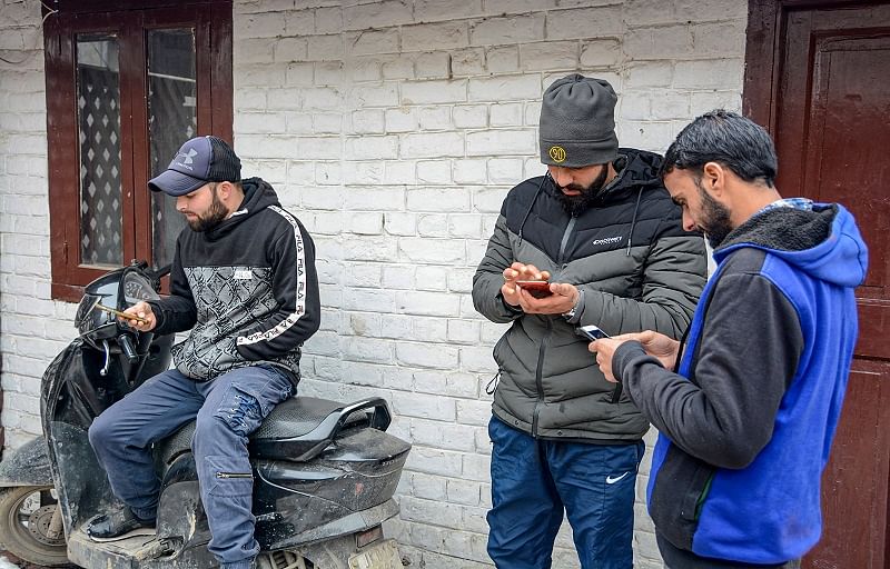 ouths use internet service on their mobile phones after government restored 2G mobile internet services, in Srinagar. (PTI Photo)