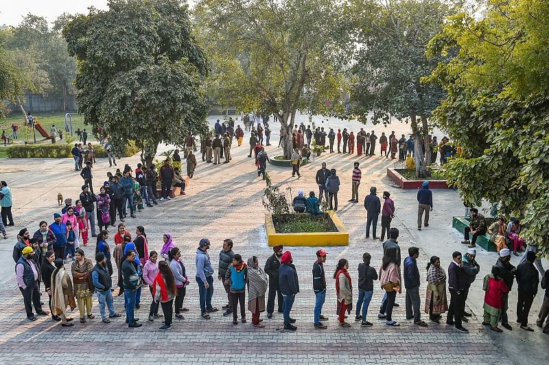 Voters stand in a queue to cast votes during the Delhi Assembly election at a polling station in Tilak Vihar, New Delhi. (PTI Photo)