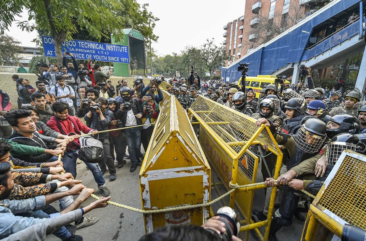 Protestors try to remove police barricades during their march against the amended Citizenship Act, NRC and NPR, near Jamia Nagar in New Delhi (PTI Photo)
