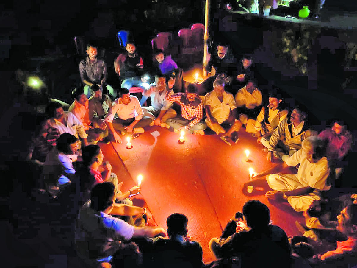 As the power supply got disrupted at the protest venue in front of the gram panchayat premises in Siddapura on Tuesday night, the flood victims continued their dharna urging for permanent rehabilitation, in candlelight. DH Photo