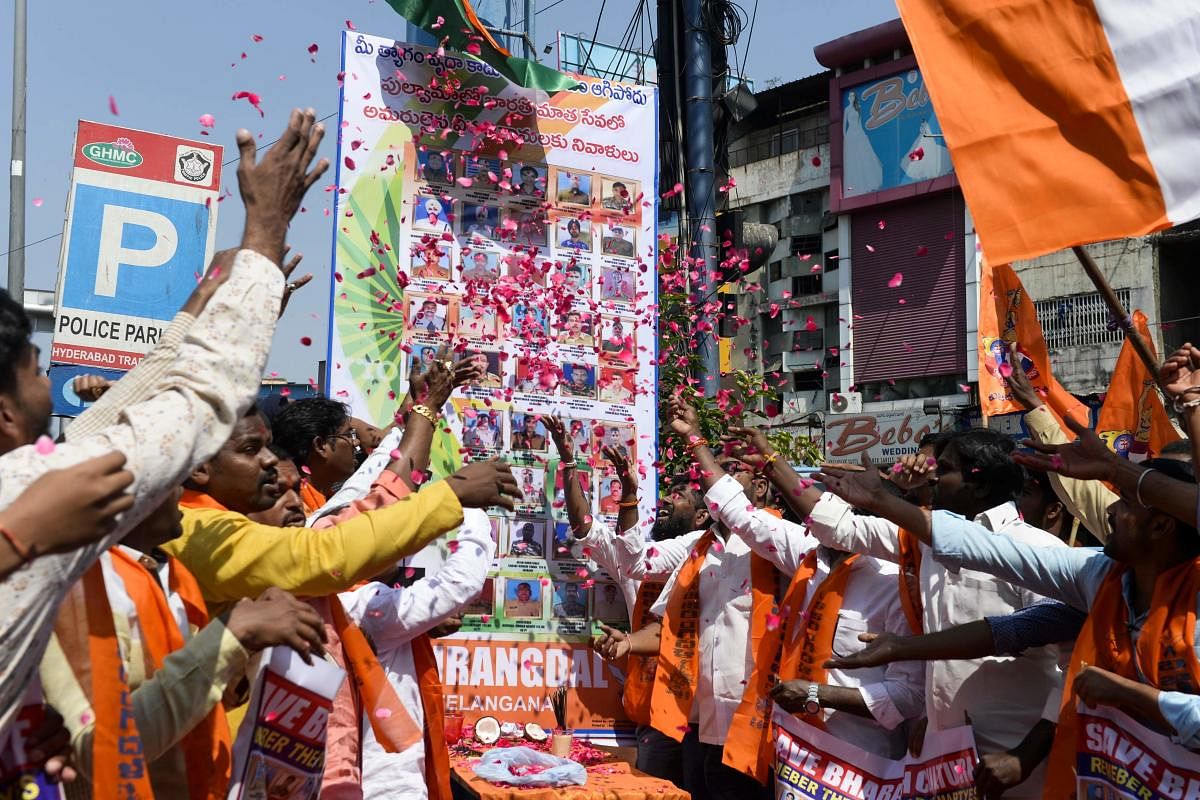Activists and supporters of Bajrang Dal, a Hindu religious group, throws rose petals on a poster with pictures of fallen Indian Central Reserve Police Force (CRPF) soldiers to mark the first anniversary of a suicide attack in Pulwama (AFP Photo)