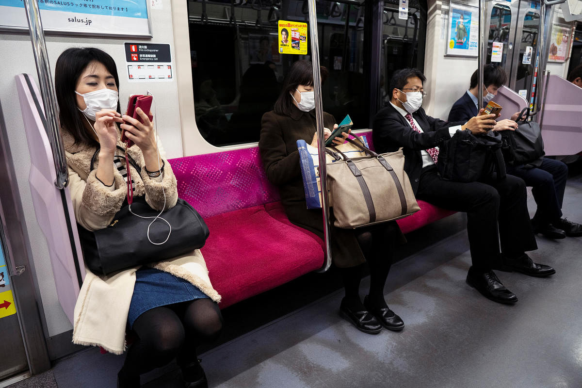Passengers wearing protective face masks are seen as they ride on a train in Tokyo (Reuters Photo)