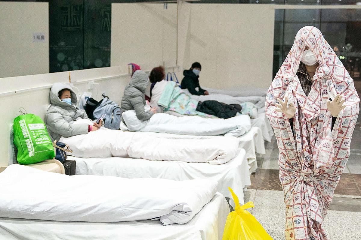A patient (R) covered with a bed sheet at an exhibition centre converted into a hospital as it starts to accept patients displaying mild symptoms of the novel coronavirus in Wuhan in China's central Hubei province. - China scrambled to find bed space for thousands of newly infected patients on February 6, as the toll from a deadly new virus jumped again with more than 28,000 people known infected nationwide and 563 deaths. (Photo by AFP)