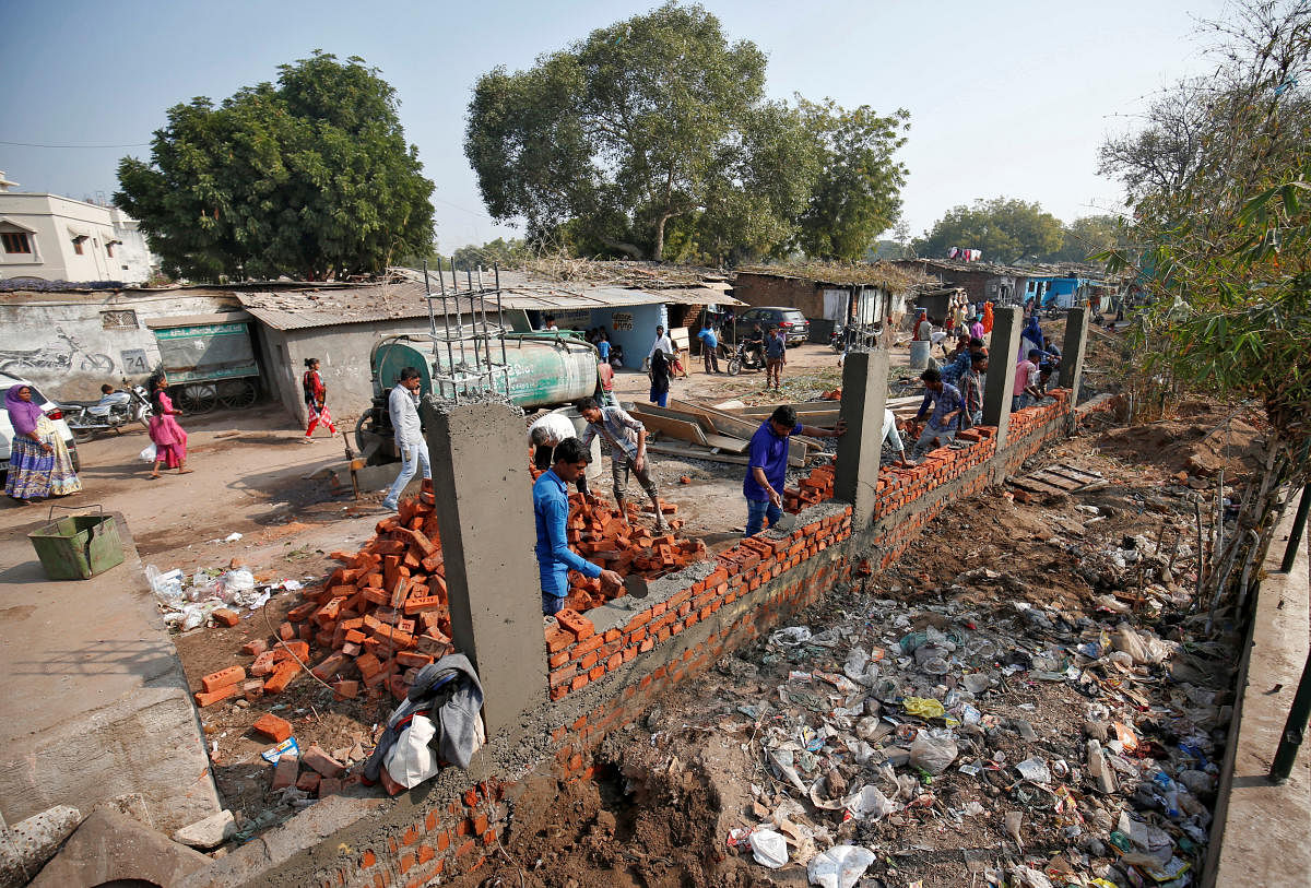 Construction workers build a wall along a slum area as part of a beautification drive along a route that US President Trump and India's PM Modi will be taking during Trump's visit later this month, in Ahmedabad. Reuters
