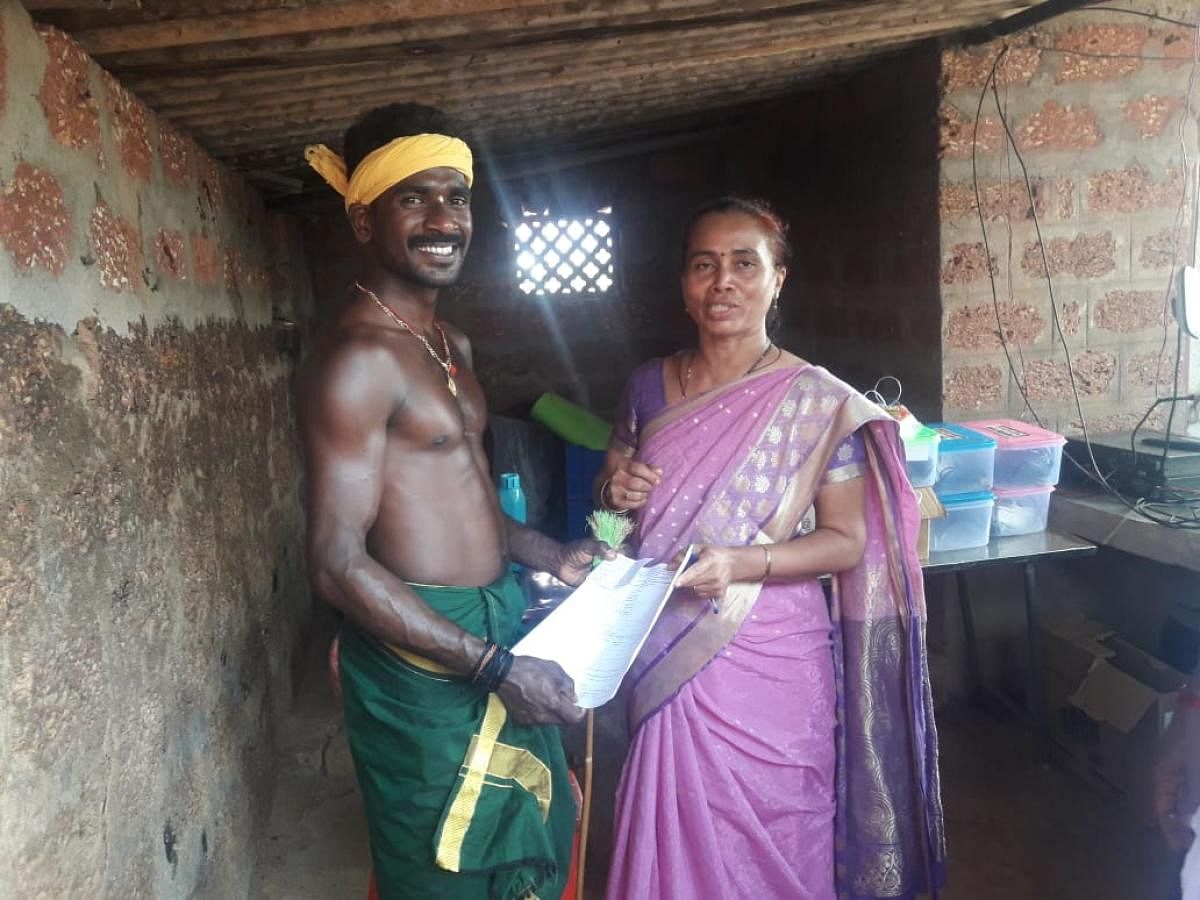 Kambla jockey Srinivasa Gowda receives the invitation for the felicitation ceremony in Bengaluru, from a labour department staffer in Venur, Moodbidri taluk. DH Photo