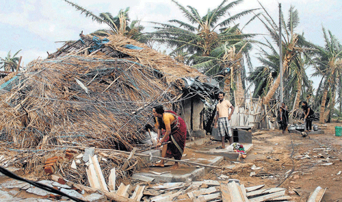 A couple salvage their damaged house at cyclone-hit Arjipalli village in Gopalpur district of Odisha on Tuesday. PTI