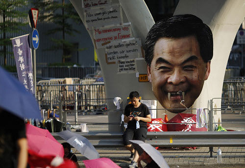 A protester sits next to cut-out of Hong Kong Chief Executive Leung Chun-ying while blocking a street outside the government headquarters in Hong Kong. Reuters photo