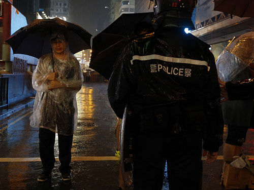 A pro-democracy protester stand in heavy rain in front of a riot policeman while blocking a road at Mongkok shopping district in Hong Kong. Eight people were detained Thursday in Hong Kong's Mong Kok area which has been occupied by protesters for over 20 days. Reuters photo