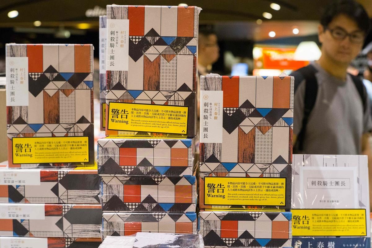 Copies of Japanese writer Haruki Murakami's latest novel 'Killing Commendatore' are displayed sealed in wrappers with yellow warning notices in a bookstore in Hong Kong. (AFP)
