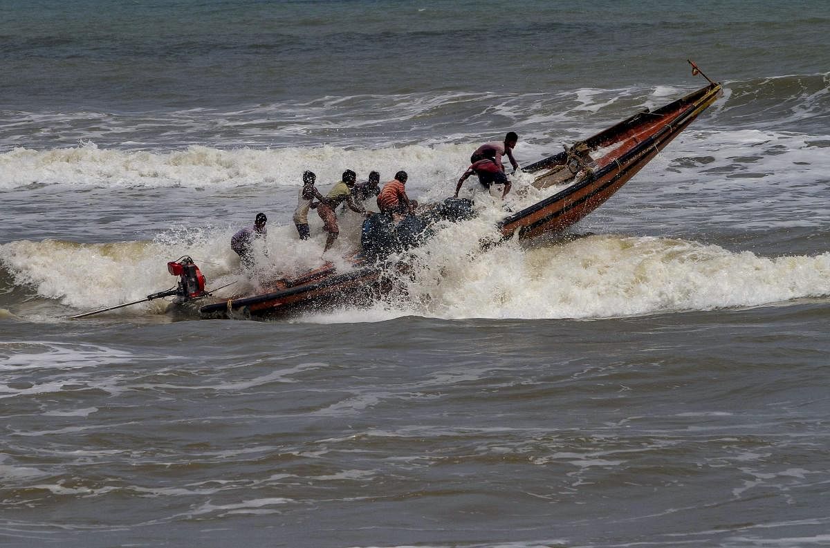 Fishermen try to control their boat amidst rough sea waters at Puri beach. PTI photo