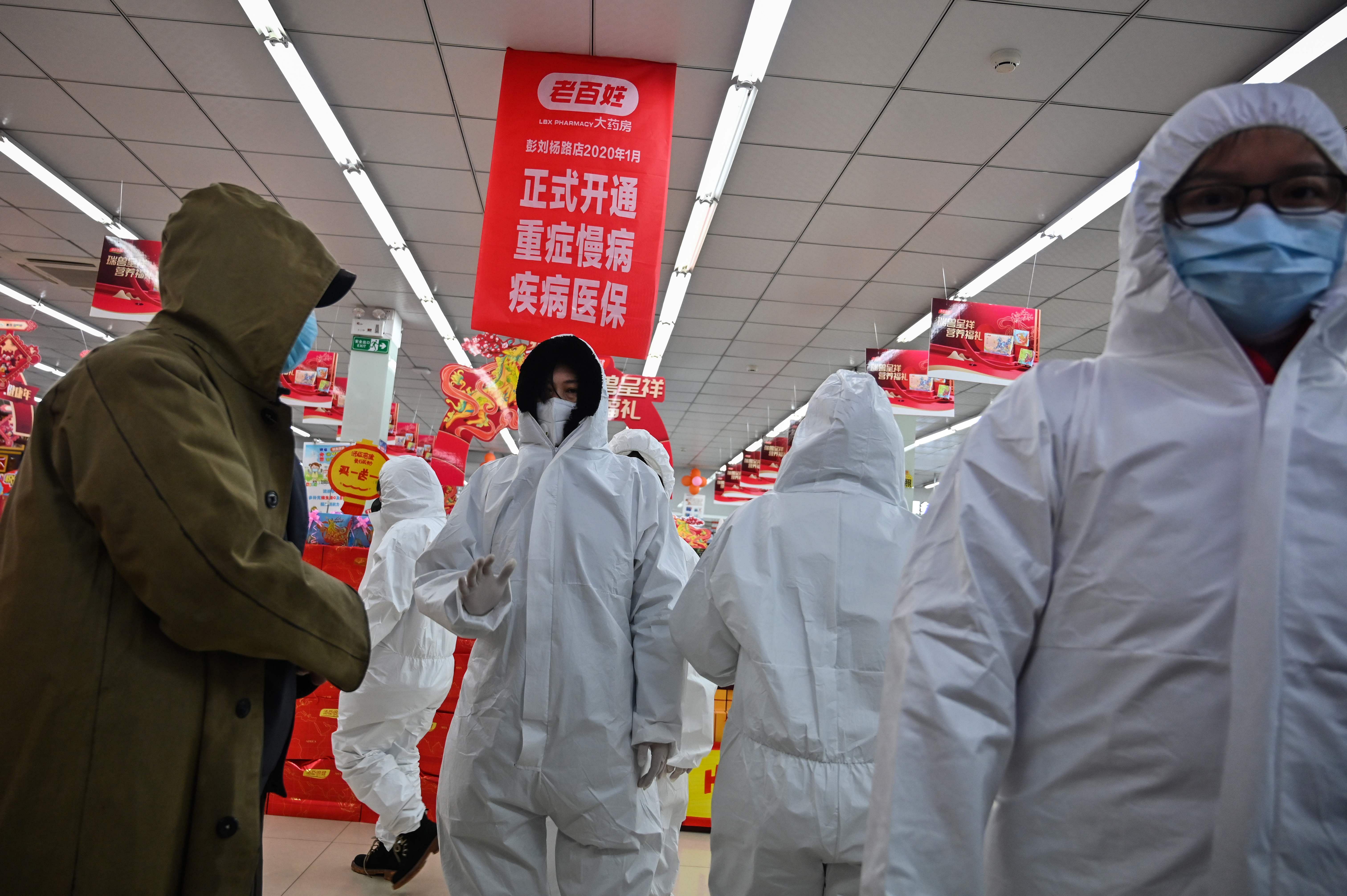 Pharmacy workers wearing protective clothes and masks serve customers in Wuhan. (AFP Photo)
