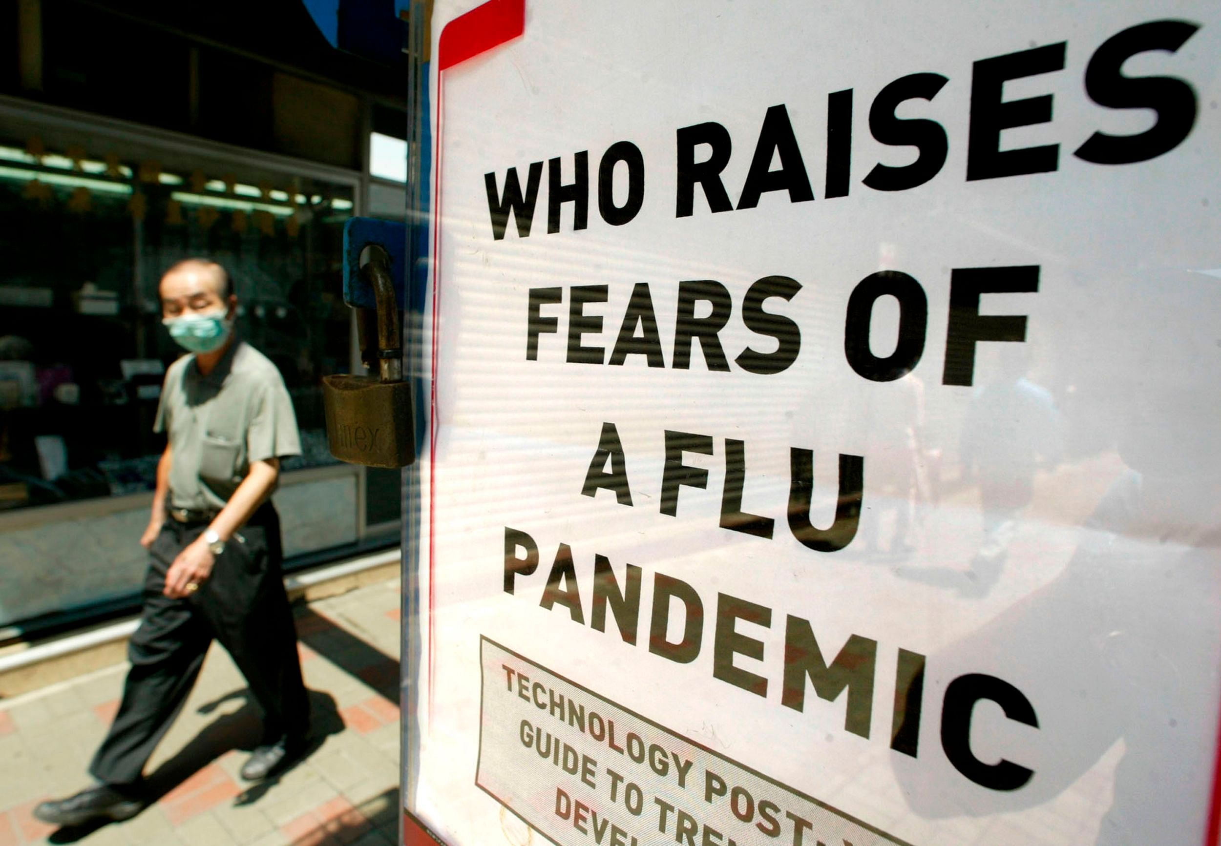 Man wearing a mask to protect against Severe Acute Respiratory Syndrome (SARS) passing a news stand poster saying that the World Health Organisation (WHO) warns that a new influenza pandemic could sweep the globe. (AFP Photo)