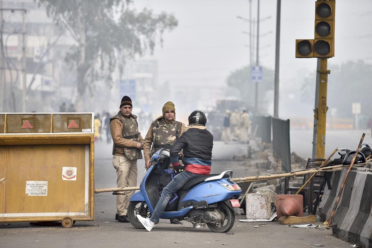 Police personnel stop a commuter as temporary barricades are set up during restrictions in view of protests against the Citizenship (Amendment) Act after Friday prayers, at Jamia Nagar, in New Delhi. (PTI photo)