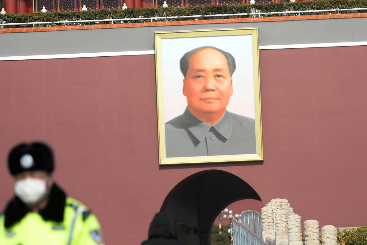 Security personnel wearing a face mask stands guard under a giant portrait of the late Chinese chairman Mao Zedong at the Tiananmen Gate, in Beijing. Credit: Reuters Photo
