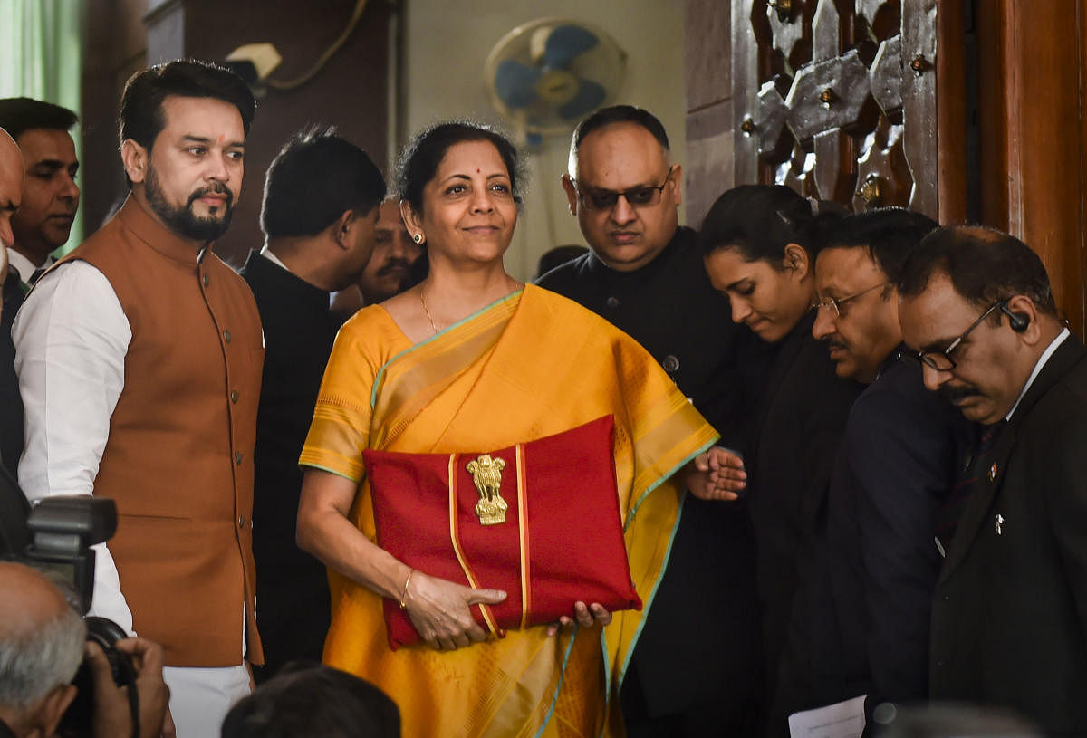 : Union Finance Minister Nirmala Sitharaman, flanked by her deputy Anurag Thakur (to her right) and a team of officials, shows a folder containing the Union Budget documents as she poses for lensmen on her arrival at Parliament. (PTI Photo)