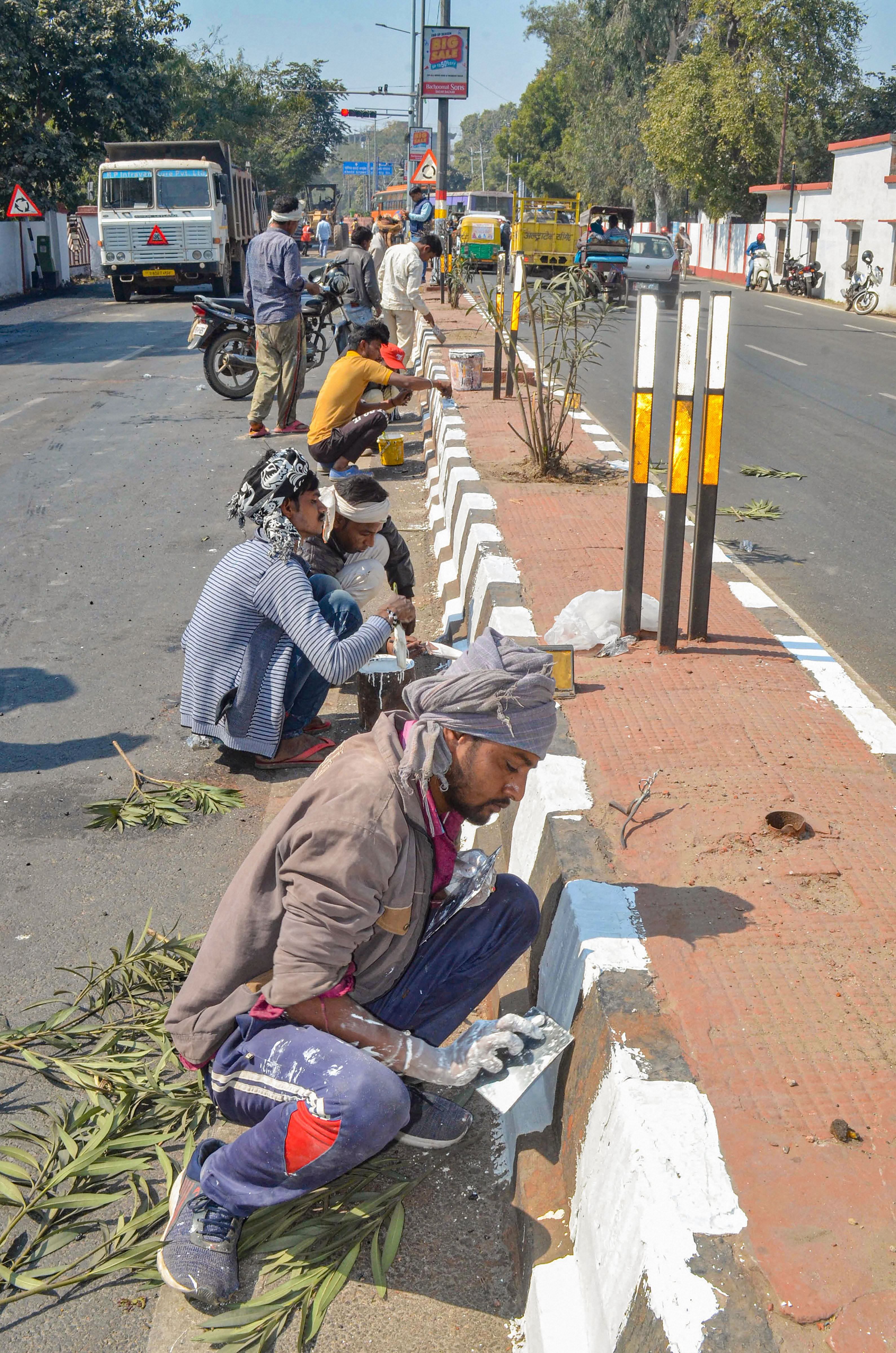 Workers paint dividers at the road from Kheria to Taj Mahal east gate, on which US President Donald Trump is expected to travel during his visit to India. (Credit: PTI Photo)