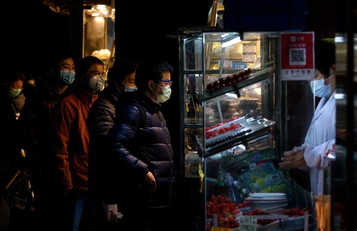 People wearing protective facemasks queue to order food from a stall in Shanghai on February 14, 2020. - Youan Hospital is one of twenty hospitals in Beijing treating coronavirus patients. AFP