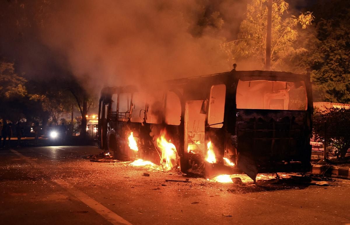 A DTC bus set on fire following protests against the passage of Citizenship Amendment Act near Mathura Road, in New Delhi. (PTI Photo)