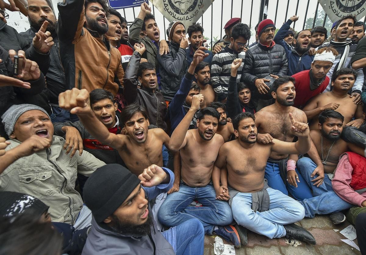 A group of Jamia Millia students stood shirtless in the bone-chilling cold outside the university gates on Monday and formed a human chain to protest the police action against their colleagues a day earlier. Photo/PTI