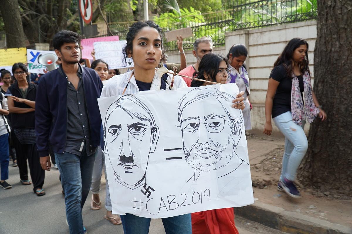 A protester shows a banner equating Hitler with Modi, in Gandhinagar on Tuesday. DH PHOTO/AKHIL KADIDAL