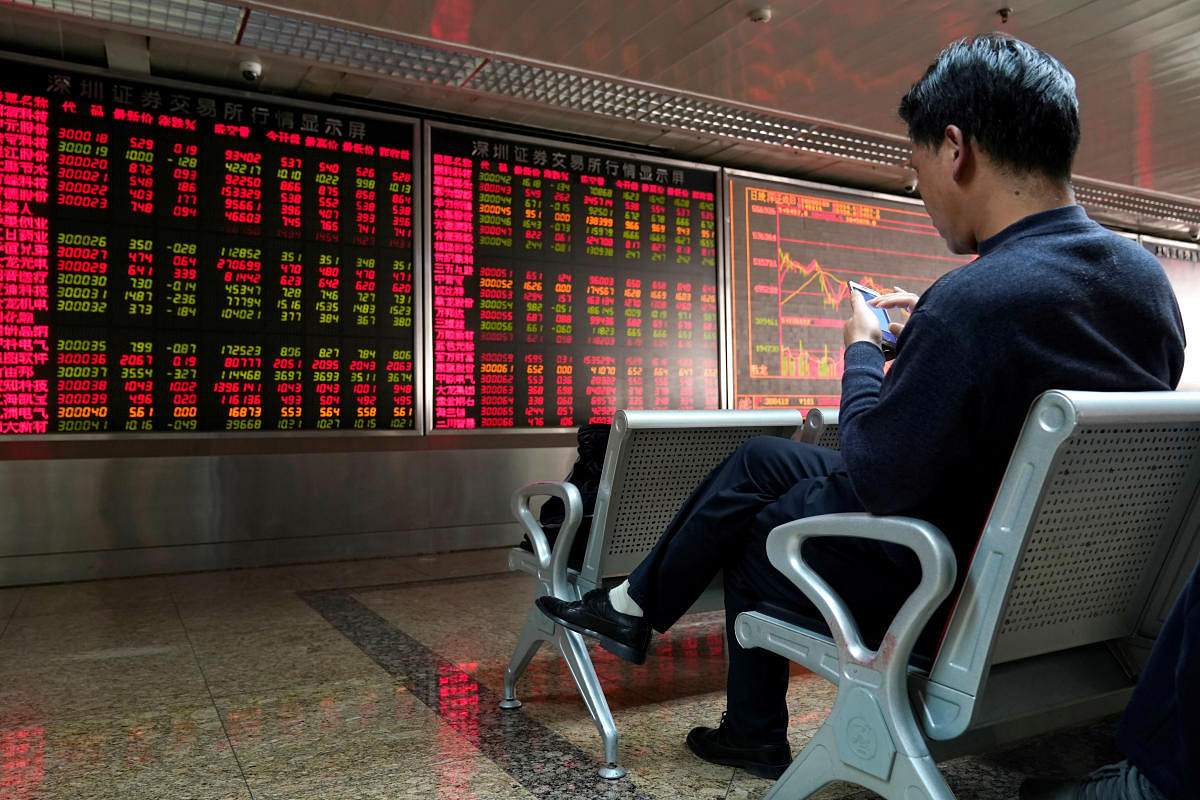An investor uses his mobile phone in front of a stock quotation board at a brokerage office in Beijing, China January 3, 2020. (Reuters Photo)