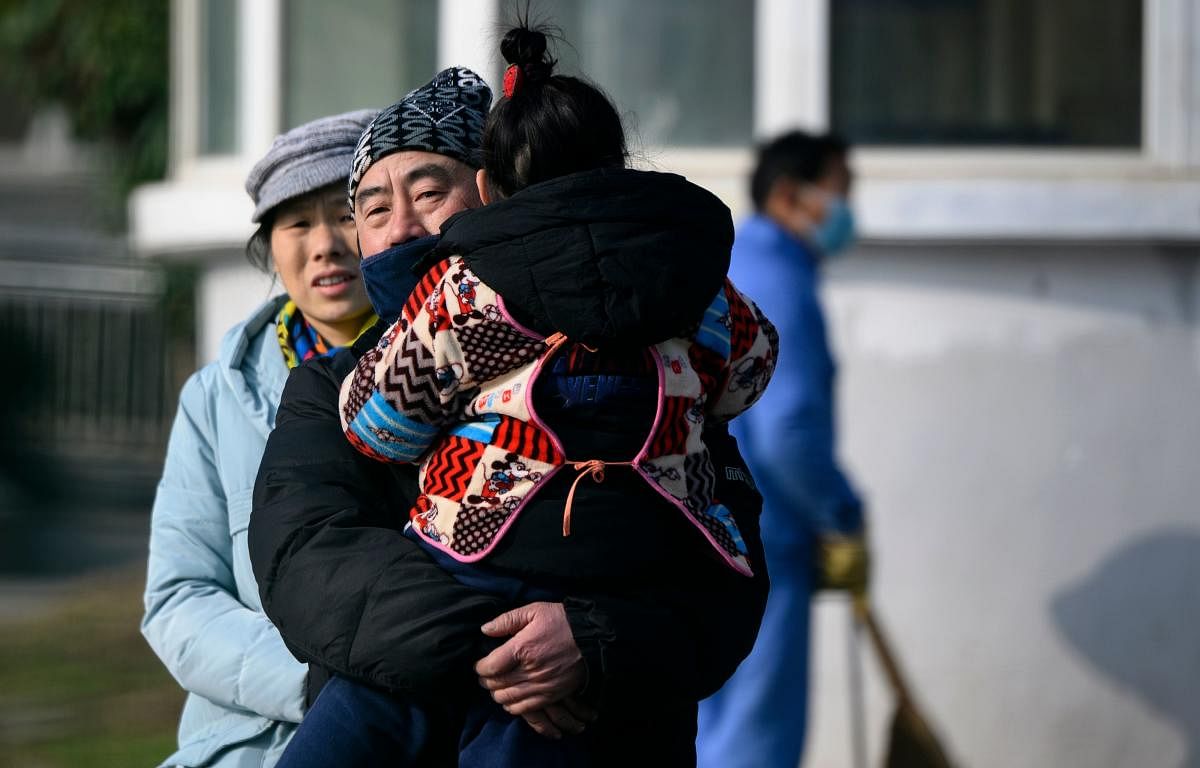 A man holding her daughter leaves the Wuhan Medical Treatment Centre, where a man who died from a respiratory illness was confined, in the city of Wuhan, Hubei province, on January 12, 2020. (AFP Photo)