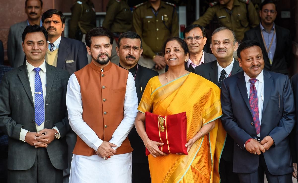 Union Finance Minister Nirmala Sitharaman, holding a folder containing the Union Budget documents, poses for photographers along with her deputy Anurag Thakur and a team of officials, outside the Ministry of Finance, North Block in New Delhi, Saturday, Feb. 1, 2020. (PTI Photo)